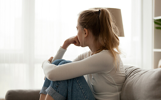 A woman sitting on a couch looking away out a window